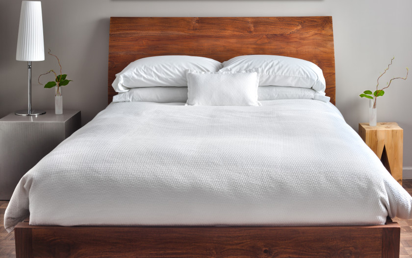 A bed with a brown wooden headboard