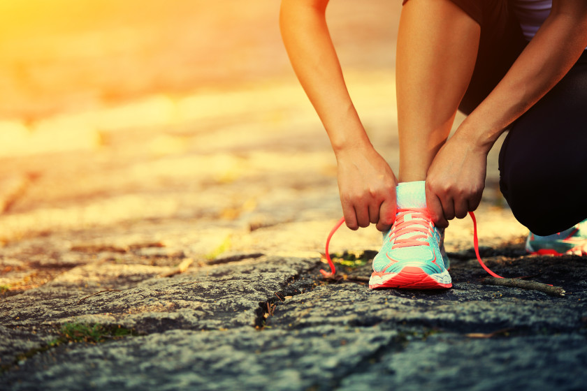 A young male student lacing up his running shoes