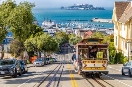 A city view of San Francisco with a tram and Alcatraz in the background