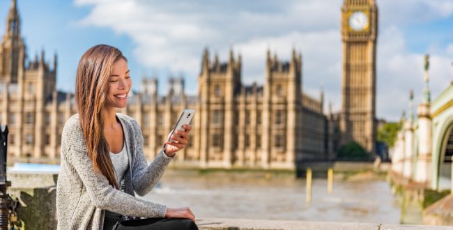 A student using her mobile phone in front of the Big Ben in London