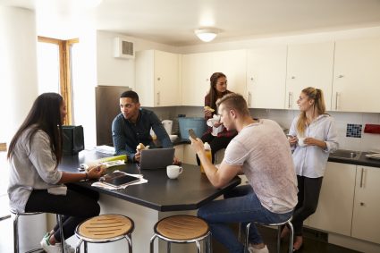 A group of students sitting around their kitchen table