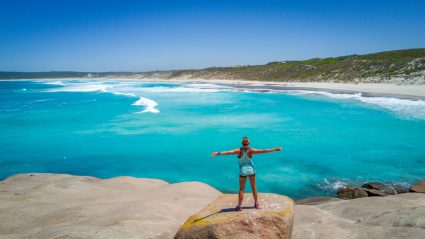 A woman standing in front of a turquoise sea