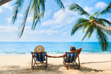 A couple sitting in deckchairs on a beach 