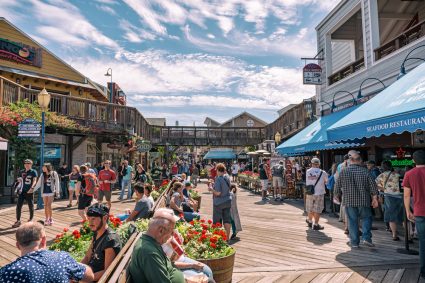 A scene of people on a boardwalk with many restaurants