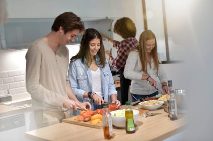 A group of students cooking together in a student housing kitchen