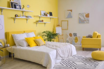 A bed with brightly coloured pillows in a student bedroom