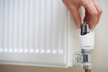 A hand turning down a radiator knob