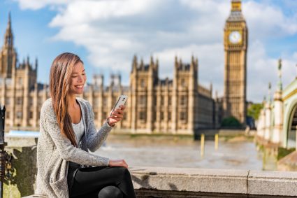 A woman using her mobile phone outside the Palace of Westminster in London