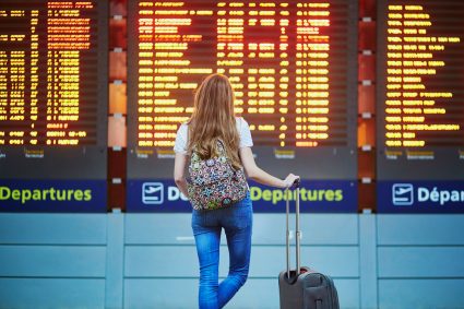 A woman standing in front of a departure board at an airport