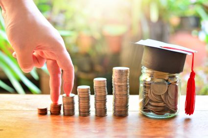 Piles of coins and a student graduation hat