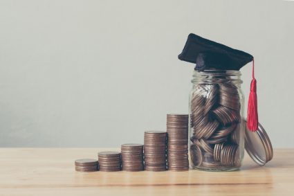 Piles of coins and a university graduation hat