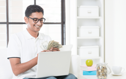 An Indian money with a laptop holding some money