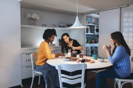 Three girls living together sitting on their kitchen table