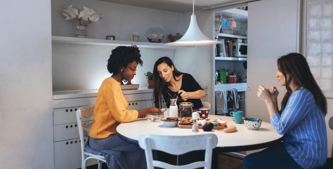 Three girls living together sitting on their kitchen table