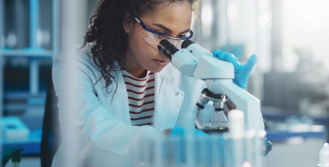 A young female biology student looking into a microscope