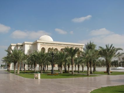 The main building of the American University of Sharjah behind a grove of palm trees