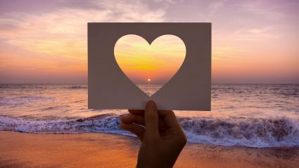 A hand made card with a cutout heart capturing sunset