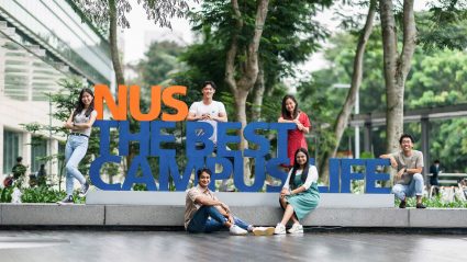 Students sitting aound a NUS cutout
